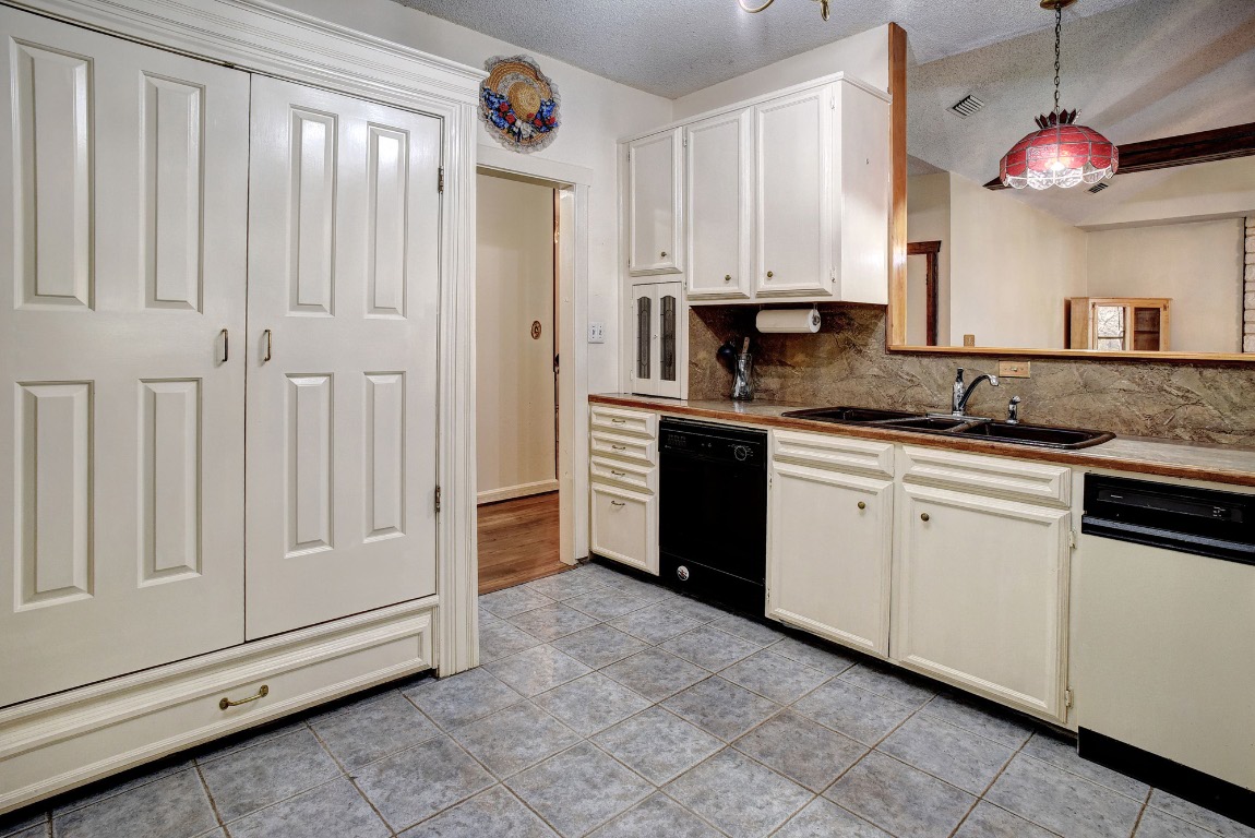 113 My Road Bastrop, TX 78602 - Photo 16 of 35 Kitchen featuring dishwasher, a textured ceiling, hanging light fixtures, tasteful backsplash, and black dishwasher