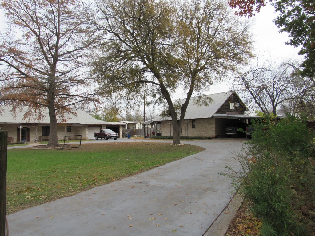 113 My Road Bastrop, TX 78602 - Photo 2 of 35 Ranch-style home with concrete driveway, a front lawn, a carport, and brick siding