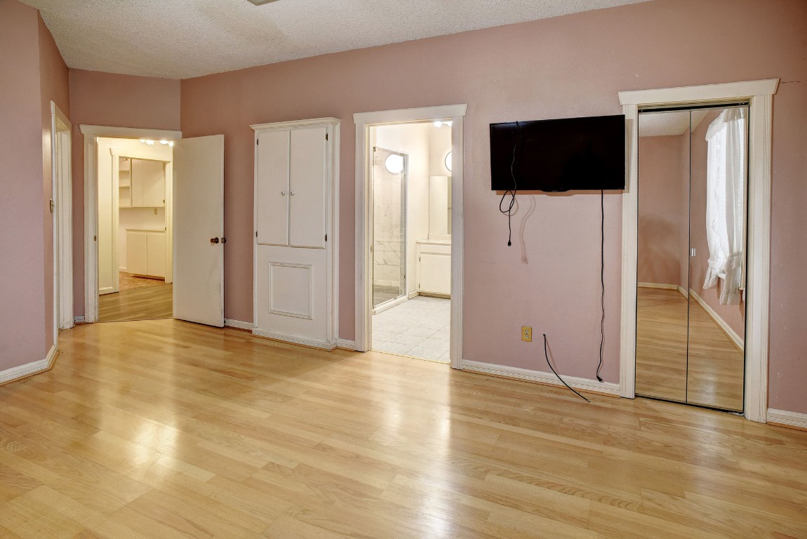 113 My Road Bastrop, TX 78602 - Photo 24 of 35 Unfurnished bedroom with a closet, light wood-style floors, a textured ceiling, and connected bathroom