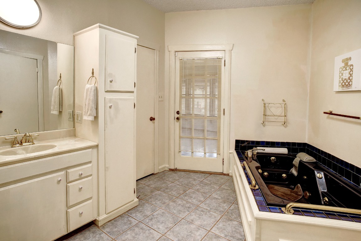 113 My Road Bastrop, TX 78602 - Photo 28 of 35 Bathroom featuring vanity, light tile patterned flooring, a jetted tub, and a textured ceiling