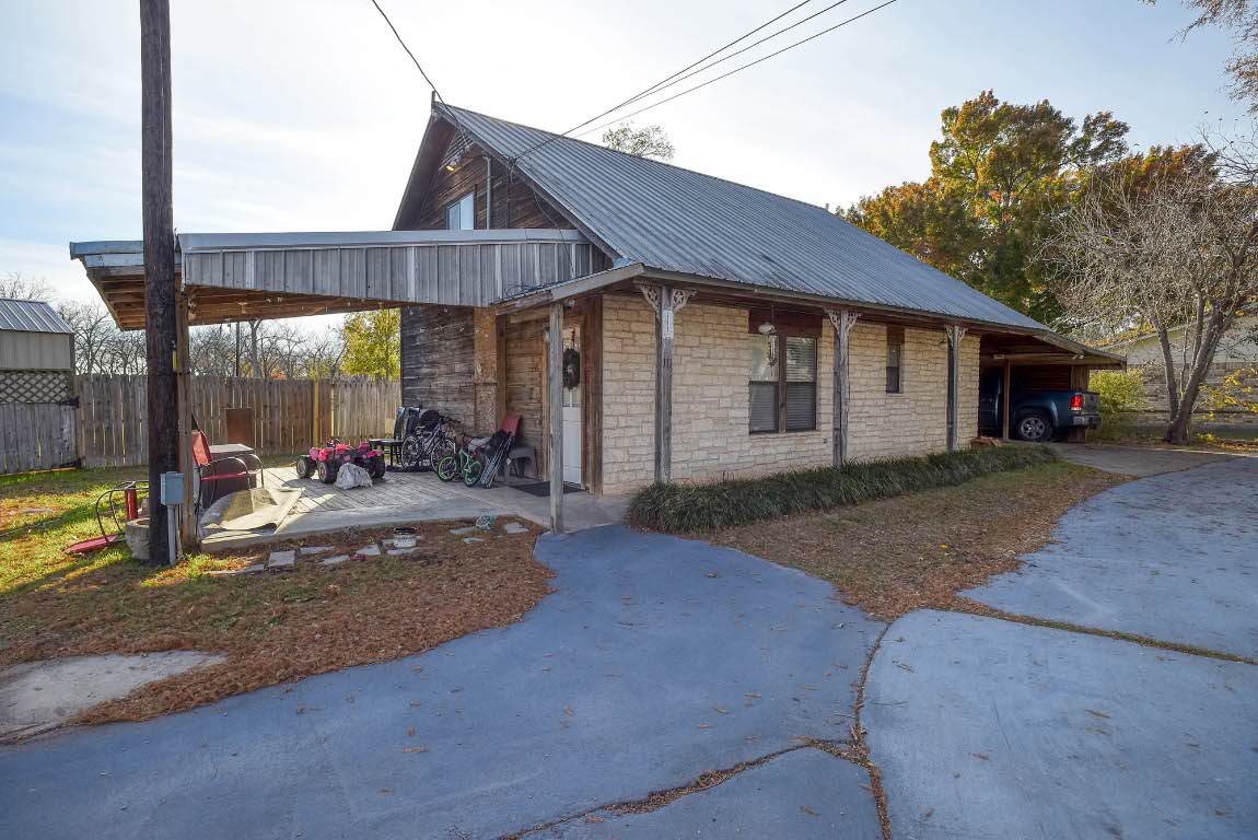 113 My Road Bastrop, TX 78602 - Photo 32 of 35 View of side of property featuring an attached carport, driveway, a metal roof, and a patio