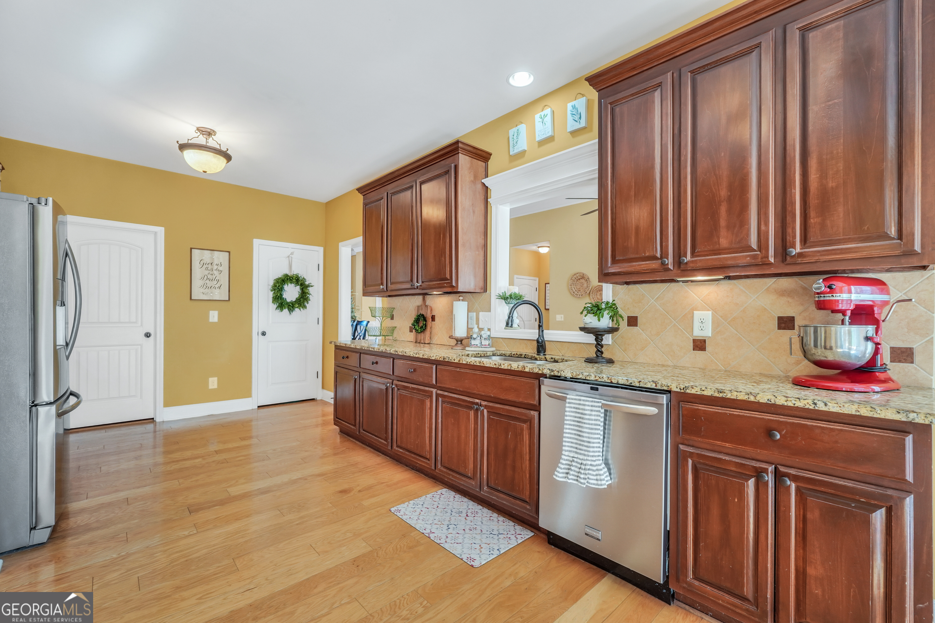 196 Magnolia Trace Milner, GA 30257 - Photo 18 of 48 a kitchen with stainless steel appliances granite countertop a refrigerator a sink dishwasher and wooden cabinets with wooden floor