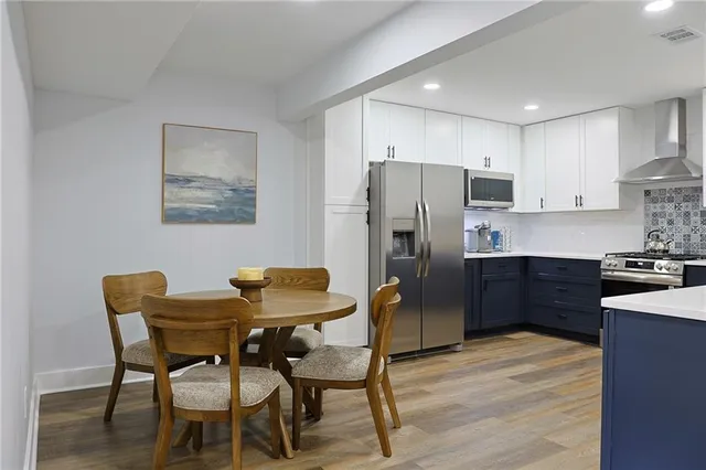 a kitchen with stainless steel appliances refrigerator dining table and chairs