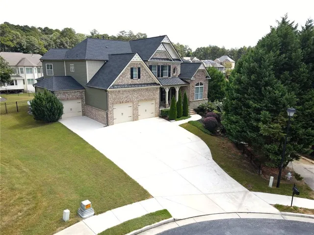 a view of a white house with a big yard plants and large tree