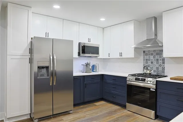 a kitchen with stainless steel appliances granite countertop a stove a refrigerator and a sink with wooden floor