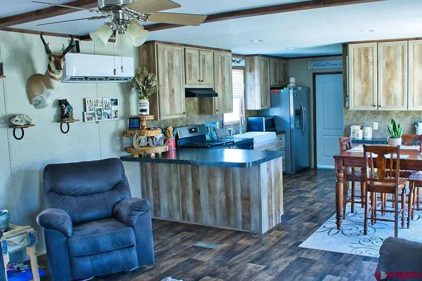 a view of kitchen with stainless steel appliances granite countertop dining table chairs sink and cabinets