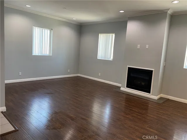 an empty room with wooden floor and stainless steel appliances