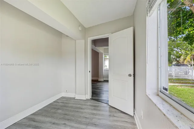 a view of a hallway with wooden floor and a room