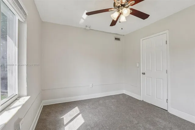 an empty room with a window and a fan