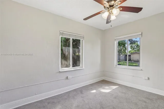 an empty room with a window and a fan