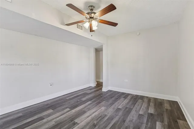an empty room with wooden floor and a ceiling fan