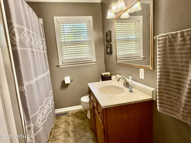 a bathroom with a sink a toilet and a window