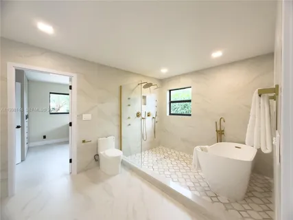 a large white bathroom with a tub shower and sink