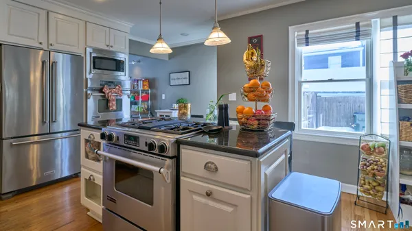 a kitchen with stainless steel appliances kitchen island granite countertop a table chairs sink and cabinets