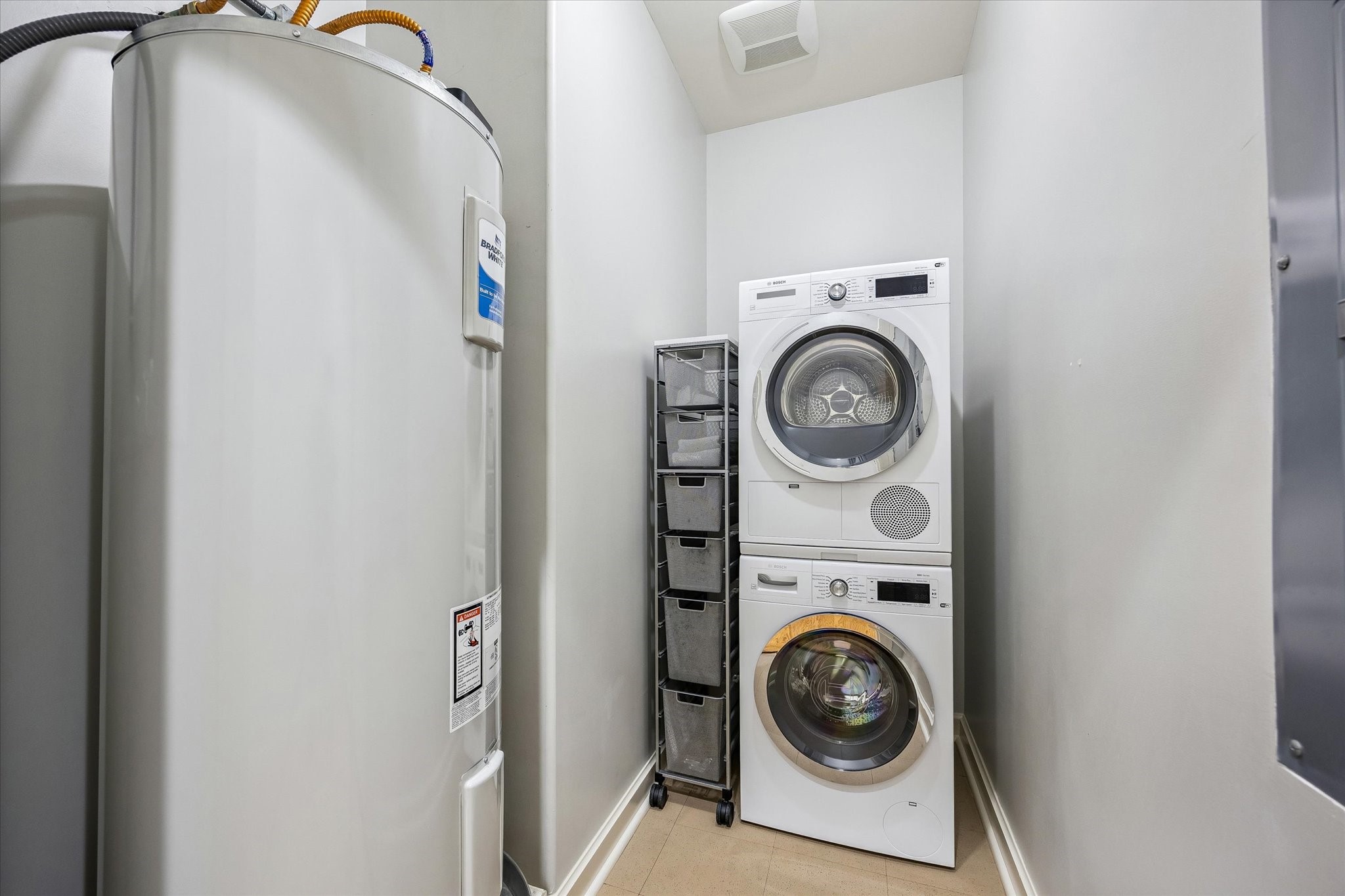 914 Main Street, Unit 910 Houston, TX 77002 - Photo 17 of 32 This laundry area features a stackable washer and dryer set, a newer large water heater, and a compact storage unit, making efficient use of space.