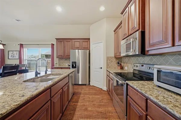 a kitchen with stainless steel appliances granite countertop a stove refrigerator sink and cabinets