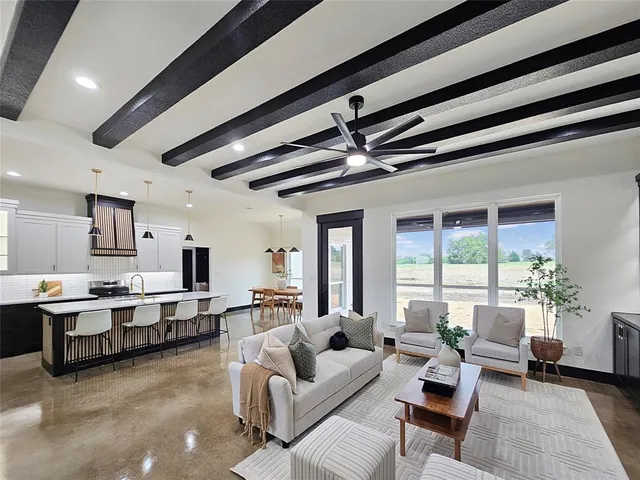 a living room with furniture kitchen view and a large window
