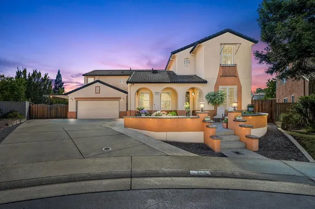 a view of a house with potted plants and a large tree