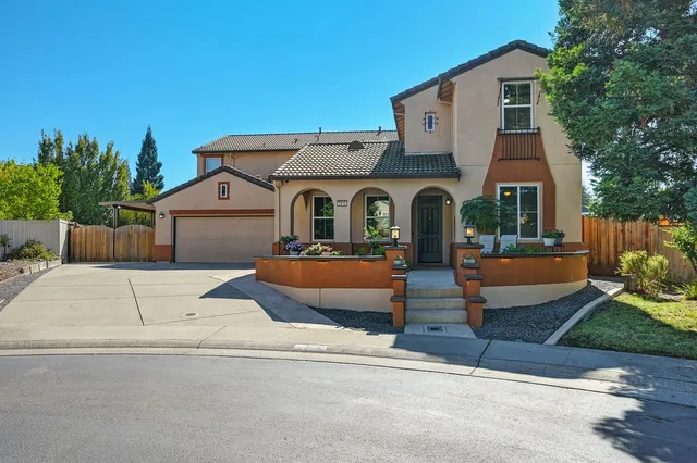 a front view of a house with lots of flowers and trees
