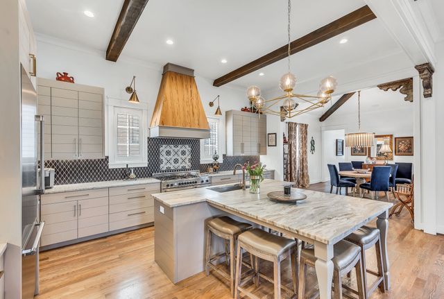 a kitchen with a stove a sink dishwasher a dining table and chairs with wooden floor