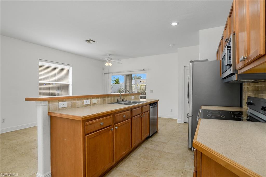 2119 River Ridge Boulevard Fort Myers, FL 33905 - Photo 4 of 19 Kitchen featuring sink, ceiling fan, stainless steel appliances, an island with sink, and decorative backsplash
