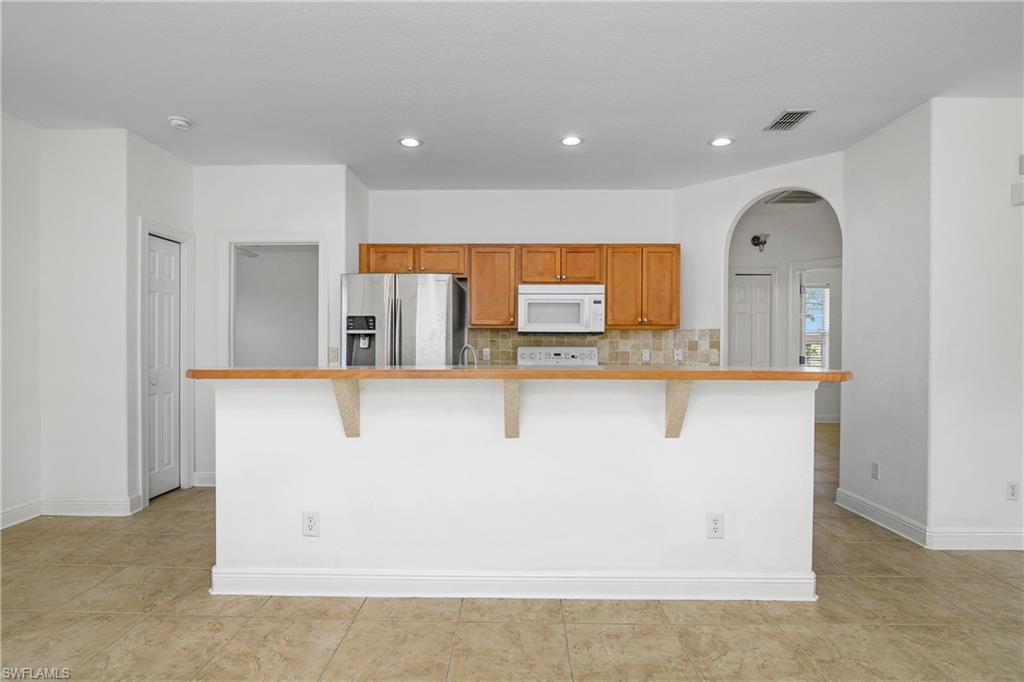 2119 River Ridge Boulevard Fort Myers, FL 33905 - Photo 7 of 19 Kitchen with stainless steel refrigerator with ice dispenser, a center island with sink, and a kitchen bar