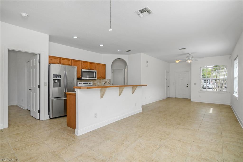 2119 River Ridge Boulevard Fort Myers, FL 33905 - Photo 8 of 19 Kitchen featuring a kitchen bar, a center island with sink, ceiling fan, stainless steel appliances, and decorative backsplash