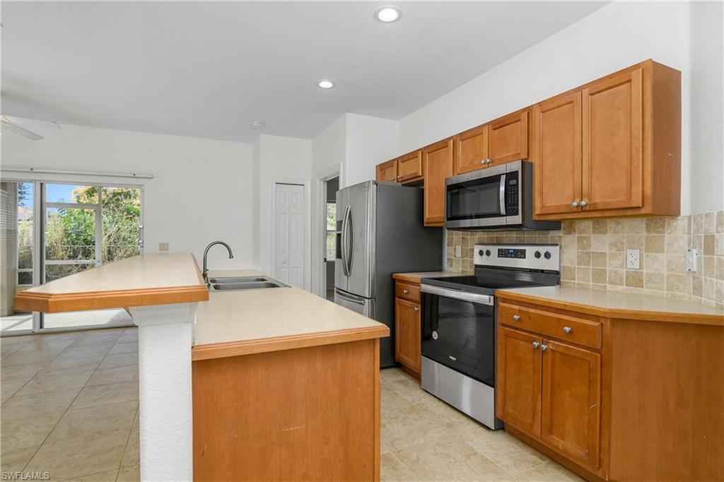 2119 River Ridge Boulevard Fort Myers, FL 33905 - Photo 9 of 19 Kitchen featuring sink, tasteful backsplash, an island with sink, ceiling fan, and stainless steel appliances
