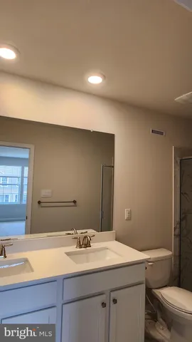 a bathroom with a granite countertop sink mirror vanity and toilet