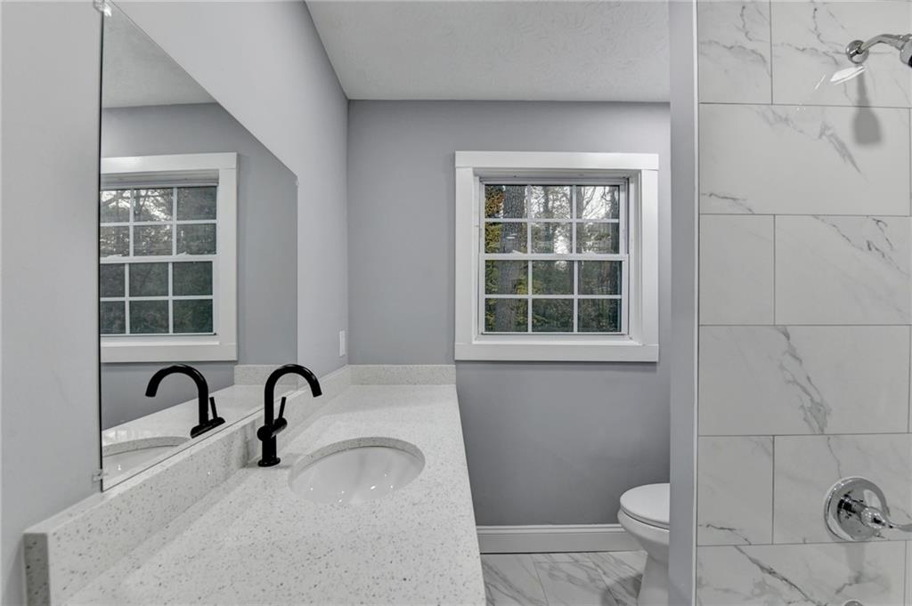 5169 Oxbow Road Stone Mountain, GA 30087 - Photo 30 of 58 a bathroom with a granite countertop bathtub sink and toilet