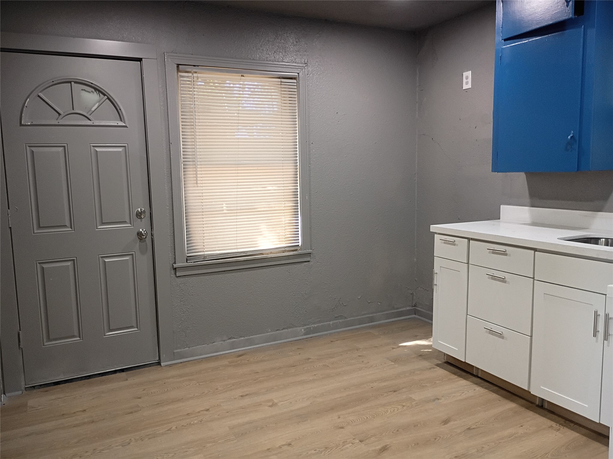 5617 Malmedy Road Houston, TX 77033 - Photo 5 of 12 an empty room with wooden floor cabinet and windows