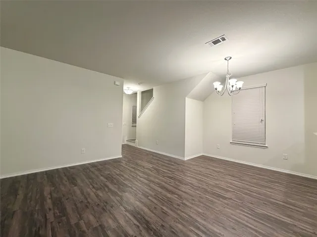 an empty room with wooden floor and chandelier