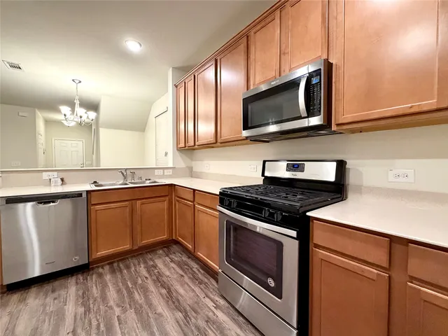 a kitchen with stainless steel appliances granite countertop a stove a microwave and wooden cabinets