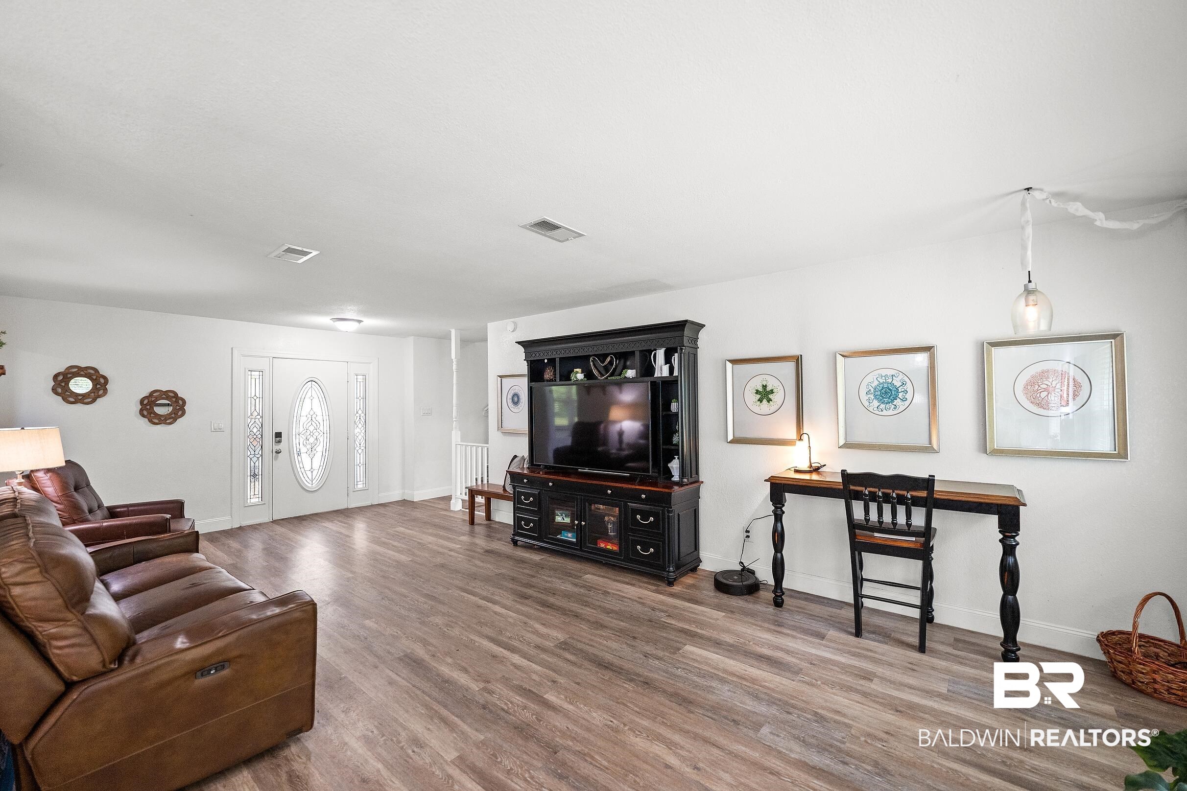33129 Antietam Road Lillian, AL 36549 - Photo 21 of 31 Bright open-concept living area featuring wood-finish flooring, white walls, and a prominent front entry door with decorative glass inserts