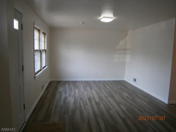 a view of an empty room with wooden floor and a fireplace