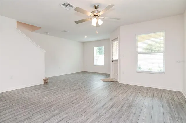 an empty room with wooden floor and windows