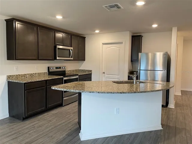 a kitchen with stainless steel appliances granite countertop a stove a sink and a refrigerator