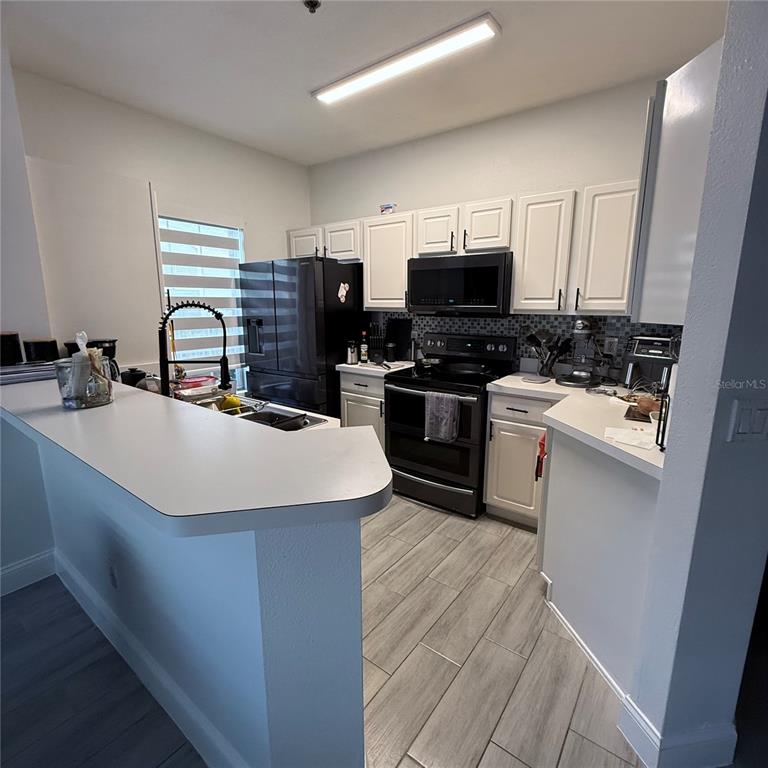 4833 Cypress Woods Drive, Unit 4112 Orlando, FL 32811 - Photo 3 of 10 a kitchen with stainless steel appliances a sink a stove a refrigerator cabinets and a counter top space