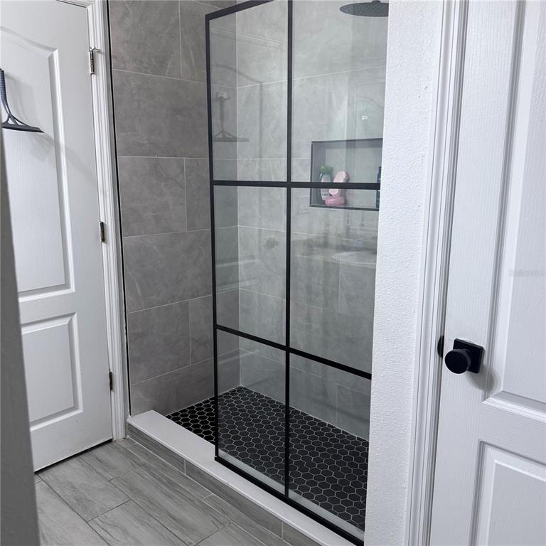 4833 Cypress Woods Drive, Unit 4112 Orlando, FL 32811 - Photo 6 of 10 a bathroom with a glass shower door