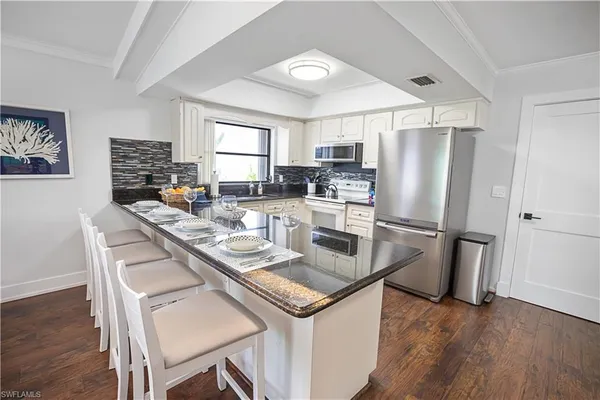 a kitchen with a table chairs stove and white cabinets