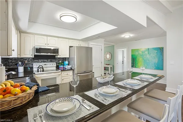 a large white open kitchen with kitchen island a stove a sink a dining table and chairs