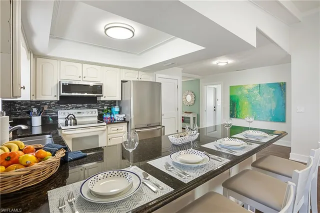 a large white open kitchen with kitchen island a stove a sink a dining table and chairs