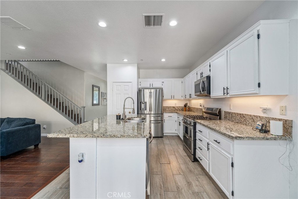 11141 Gardenhurst Court Riverside, CA 92505 - Photo 8 of 65 a kitchen with stainless steel appliances granite countertop a sink a stove a refrigerator and white cabinets with wooden floor
