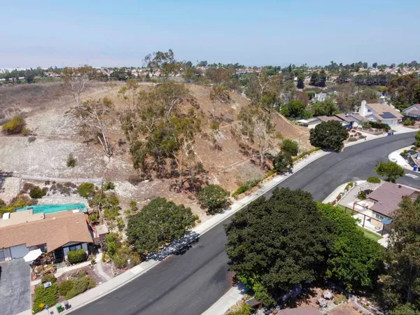 an aerial view of a house with a yard and mountain view in back