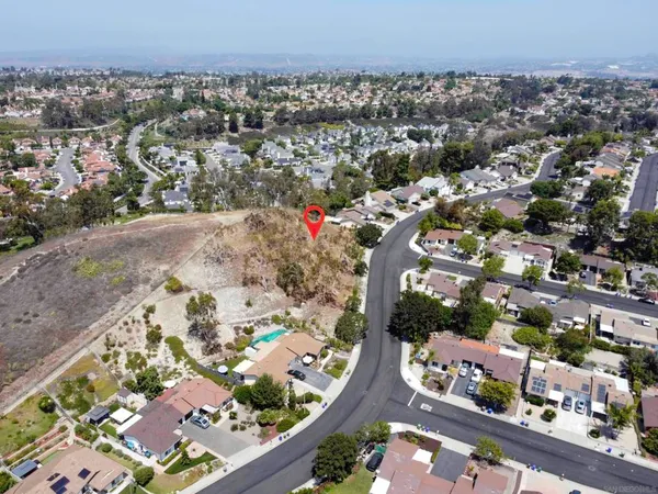 an aerial view of a house with a yard and covered with trees