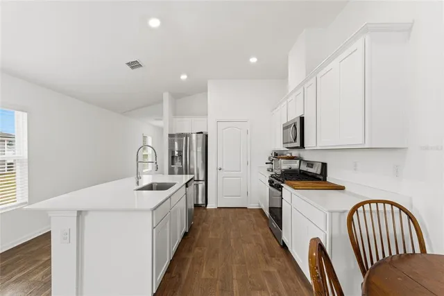 a kitchen with sink a refrigerator and white cabinets