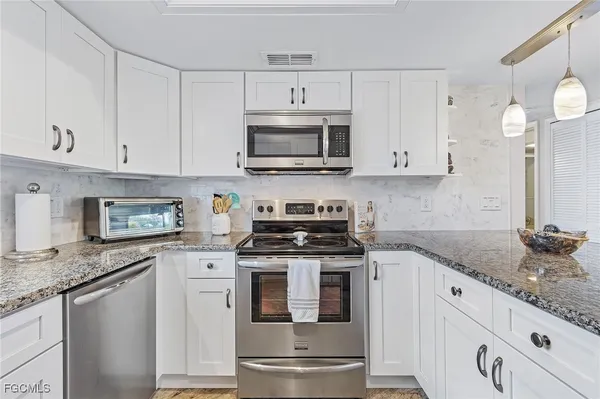 a kitchen with granite countertop white cabinets white stainless steel appliances and a sink