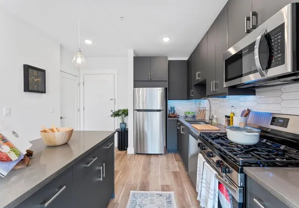 a kitchen with stainless steel appliances granite countertop a stove a sink dishwasher a refrigerator and a microwave oven with wooden floor