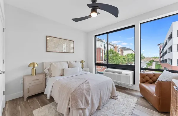 a bedroom with a bed couch and large window