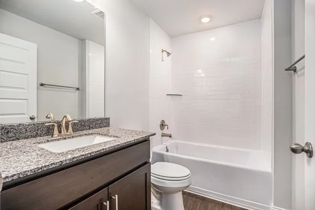 a bathroom with a granite countertop sink toilet and shower